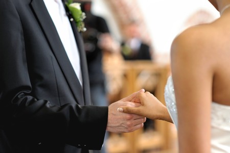 Bride and groom holding each other's hands during wedding ceremony