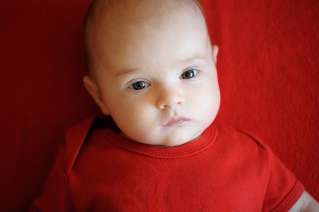 Two month baby laying on a bright red blanketの写真素材