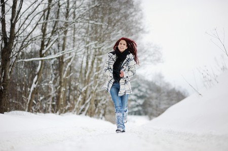 Young woman having a walk in snowy forestの写真素材