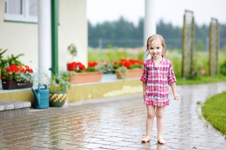 Little girl having fun under the rain in summerの写真素材