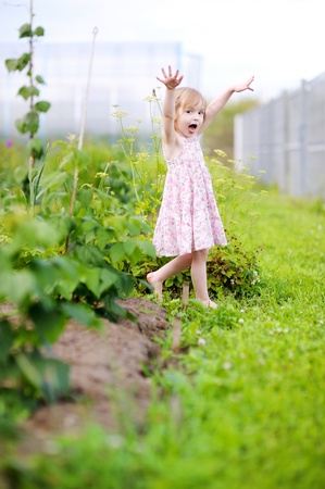 Adorable little girl fooling around in a gardenの写真素材