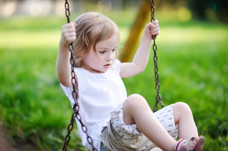 Adorable little girl having fun on a swingの写真素材