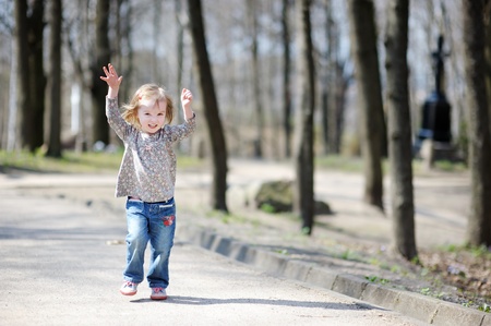 Adorable happy toddler girl jumping outdoorsの写真素材