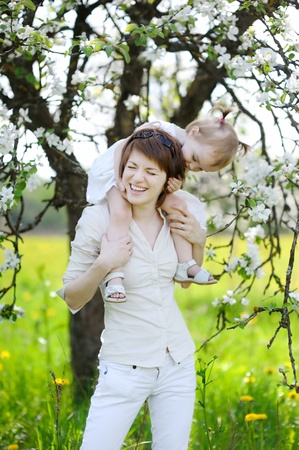 Young mother and her daughter in blossoming apple treesの写真素材