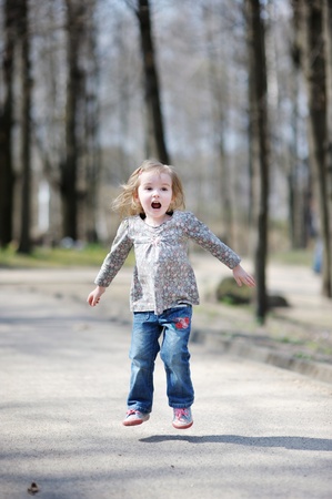 Adorable happy toddler girl jumping outdoorsの写真素材