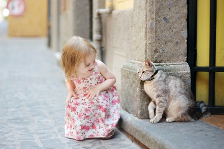 Adorable happy little girl and a cat outdoorsの写真素材