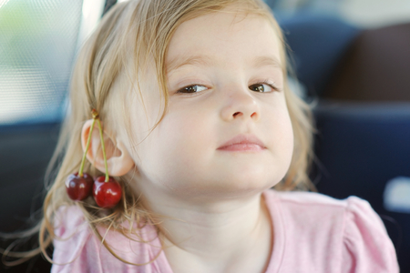 Adorable little girl with a cherry on her earの写真素材