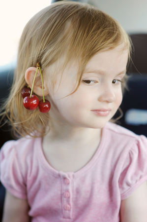 Adorable little girl with a cherry on her earの写真素材