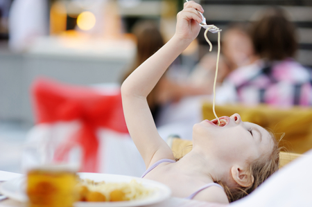 Cute little girl eating spaghetti outdoorsの写真素材