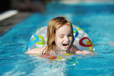 Pretty little girl swimming in outdoor poolの写真素材