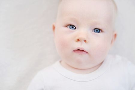 Adorable baby girl portrait on a white blanketの写真素材