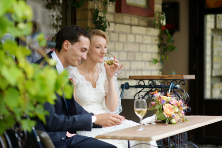 Bride and groom drinking wine at an outdoor cafeの写真素材