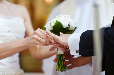 Bride putting a ring on groom's finger during wedding ceremonyの写真素材
