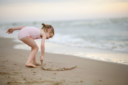 Little girl drawing on a sandの写真素材