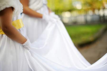 Little bridesmaids holding bride's wedding dressの写真素材