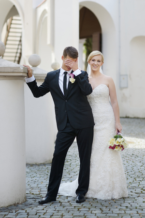 Bride and groom laughing and covering his faceの写真素材