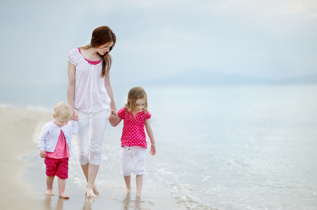Mother and her two girls walking along a beachの写真素材