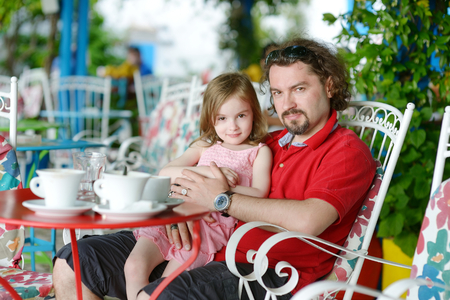 Father and daughter relaxing in outdoor restaurantの写真素材