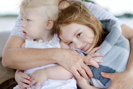 Mother's hands embracing two little sistersの写真素材