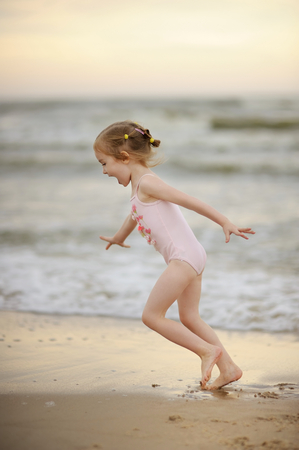 Little girl playing on a beach at sunsetの写真素材