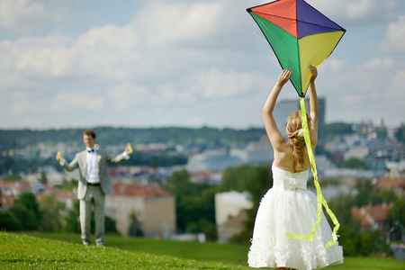 Bride and groom flying a kite together on a wedding dayの写真素材