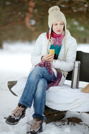 Young woman picnicking in the park at winterの写真素材