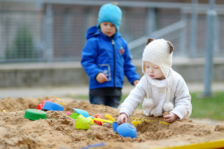 Two kids playing in a sandbox on autumn dayの写真素材