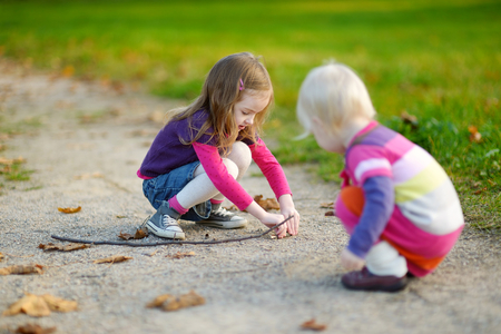 Two little sisters having fun in beautiful autumn parkの写真素材