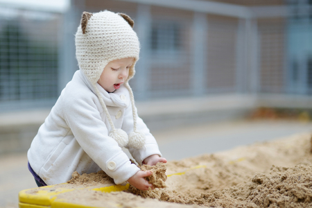 Adorable toddler girl playing in a sandbox on autumn dayの写真素材