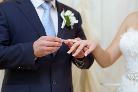 Groom is putting the wedding ring on bride's fingerの写真素材