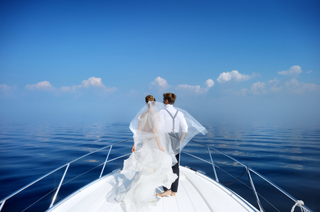 Happy bride and groom hugging on a yachtの写真素材