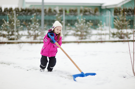 A young girl takes pride in completing a big shoveling jobの写真素材