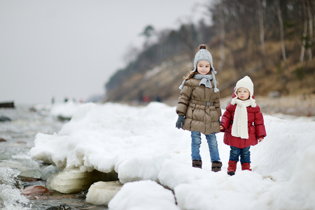 Two little sisters by the sea on winter dayの写真素材