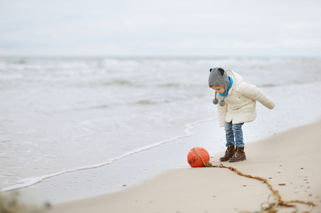 Adorable little girl playing by the ocean on winter dayの写真素材