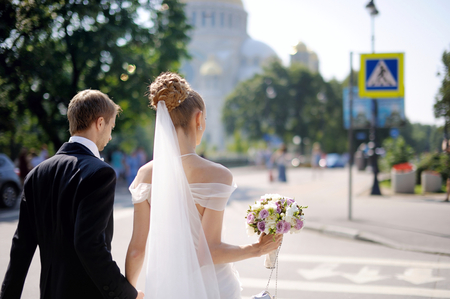 Happy bride and groom walking across the streetの写真素材