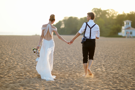 Happy bride and groom on a beautiful beach on sunsetの写真素材