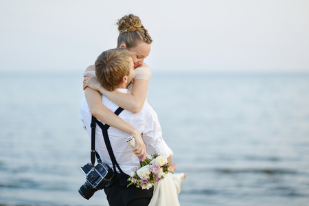 Beach wedding: bride and groom hugging by the seaの写真素材