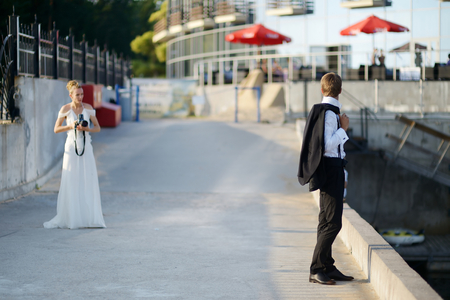Groom posing while his bride is shooting with an old cameraの写真素材
