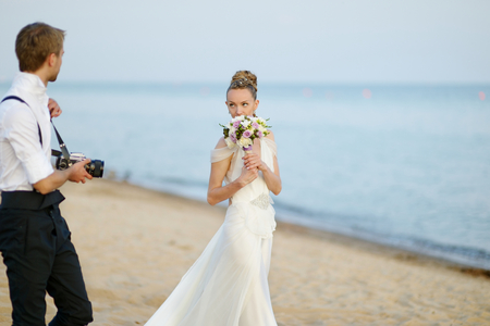 Bride posing while her groom is shooting with an old cameraの写真素材