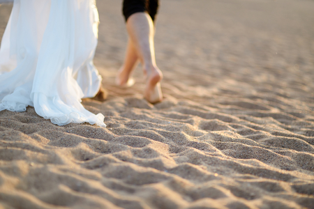 Happy bride and groom on a beautiful beach on sunsetの写真素材