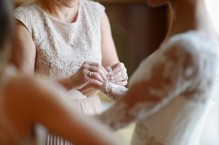 Helping the bride to put her wedding dress onの写真素材