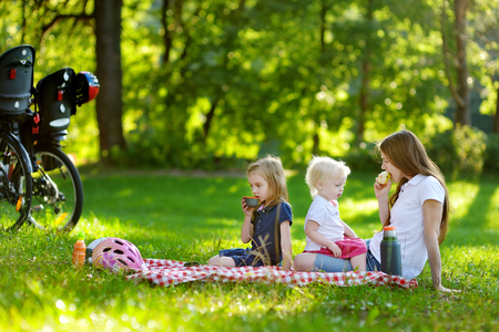 Young mother and her daughters picnicking in the parkの写真素材