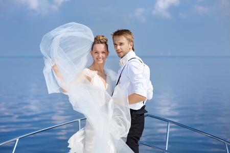 Happy bride and groom hugging on a yachtの写真素材