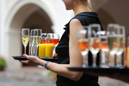 Waiter with dish of champagne, wine and juice glassesの写真素材