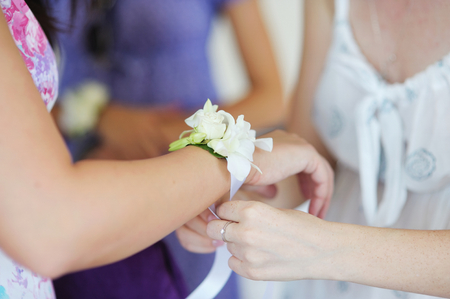 Adjusting a white boutonniere on a bridesmaid handの写真素材