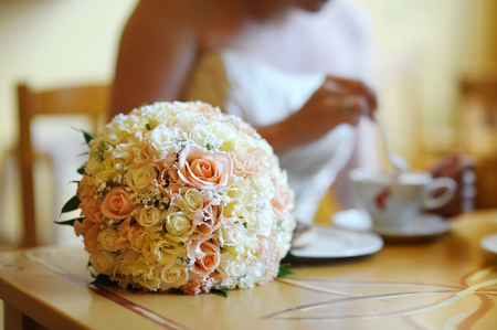 Bridal wedding bouquet on a table (bride on a background)の写真素材