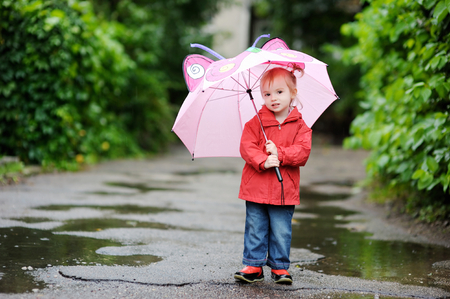 Adorable toddler girl at rainy day in autumnの写真素材