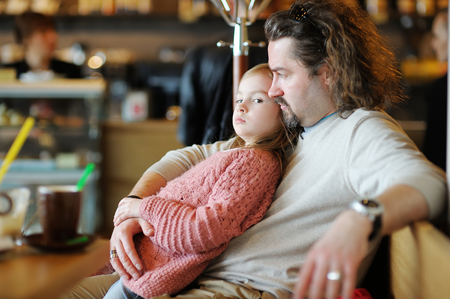 Father and his daughter relaxing in a restaurantの写真素材