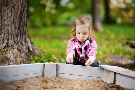 Adorable little girl playing in a sandboxの写真素材