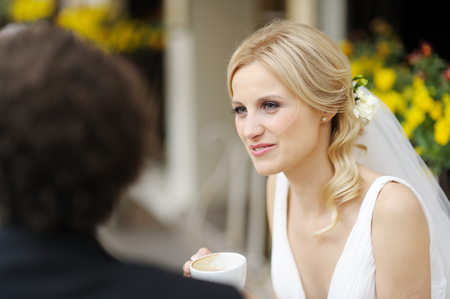 Bride and groom drinking coffee at an outdoor cafeの写真素材